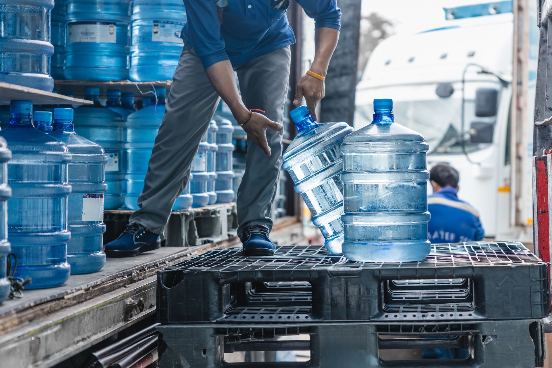 worker transfer drinking water bottle from production plant line to truck for customer market