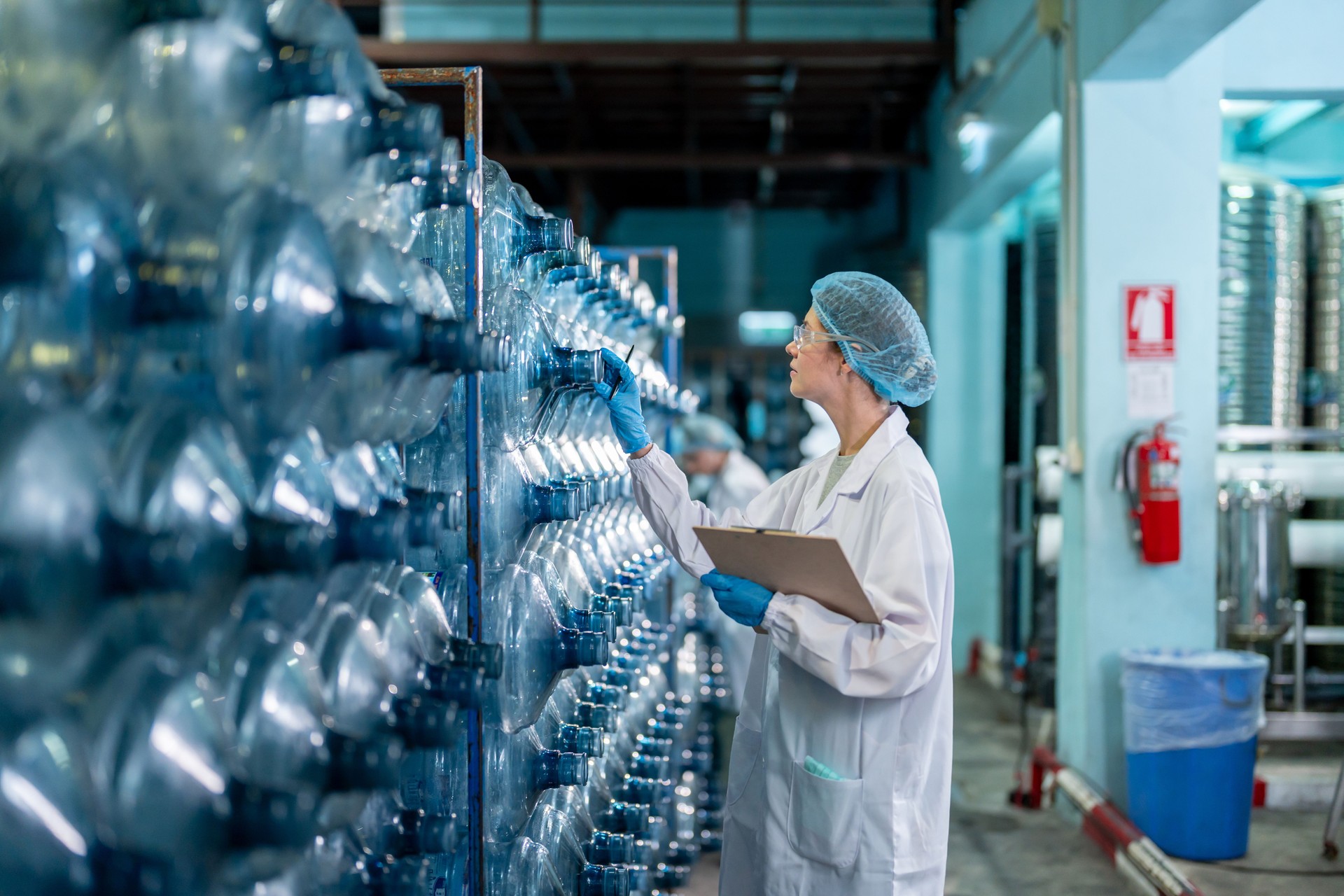 Caucasian female scientist working in laboratory at factory warehouse. Attractive woman chemist analysis of a chemical sample in the scientific research laboratory processing bottles of mineral water.